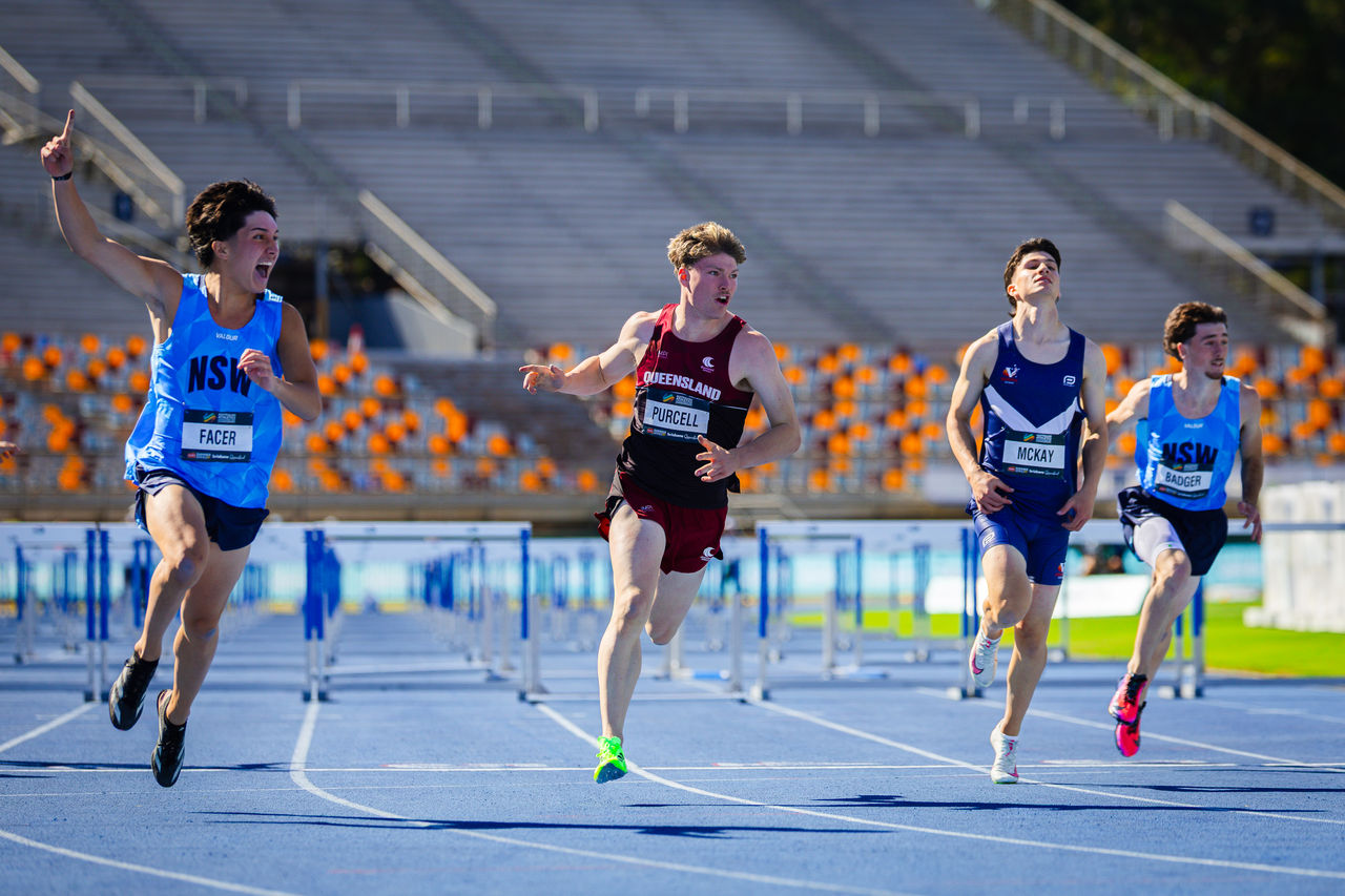 Four athletes running on the State Athletics Facility track
